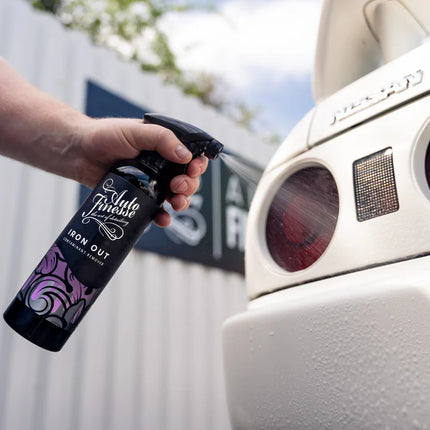 Sprej Auto Finesse Iron Out v ruce na části karoserie