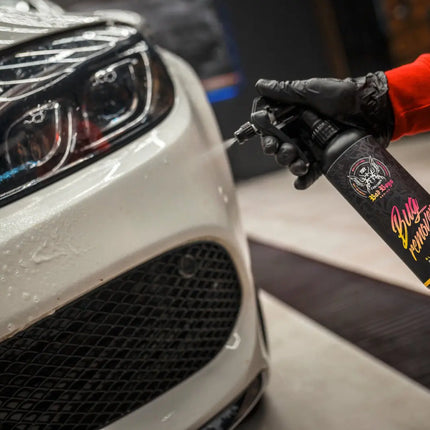 Sprej na auto v rukavici, čištění u předního světla bílého vozu.